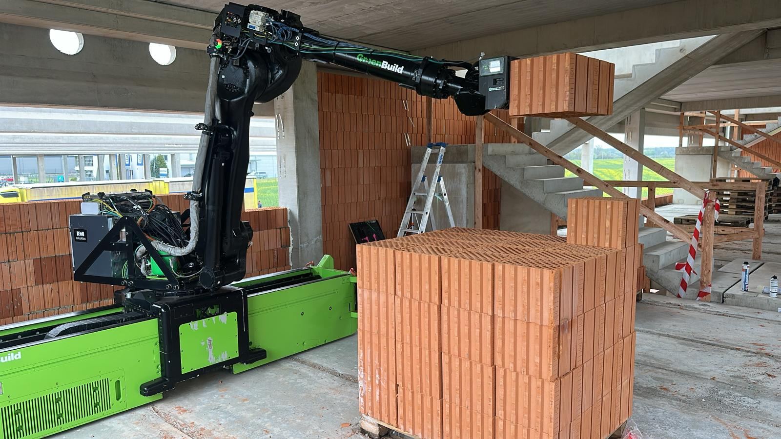Roboterarm beim Handling einer Ziegelpalette auf der Baustelle